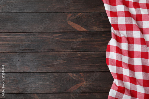 Checkered picnic blanket on wooden background, top view. Space for text