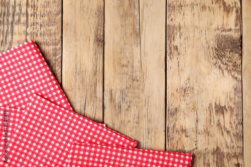 Checkered picnic napkins on wooden background, top view. Space for text