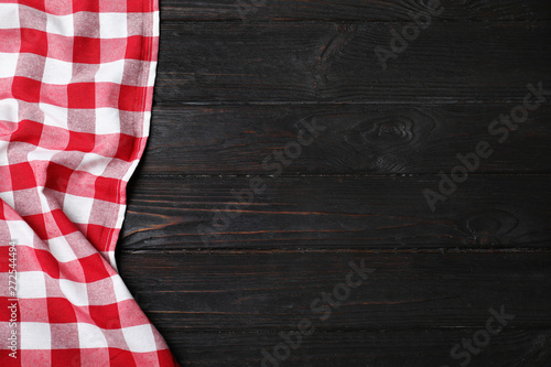 Checkered picnic blanket on color wooden background, top view. Space for text