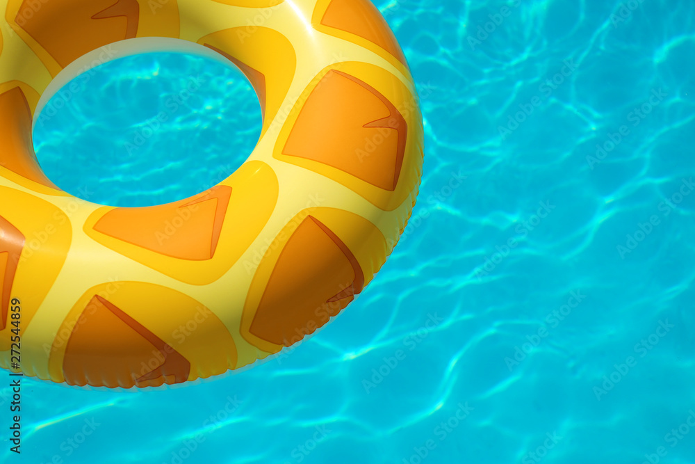 Bright inflatable ring floating in swimming pool on sunny day. Space for text