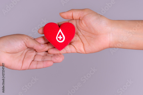 Woman hand gives a red heart to a boy hand for blood donation concept,World blood donor day. Copy space for advertisers.