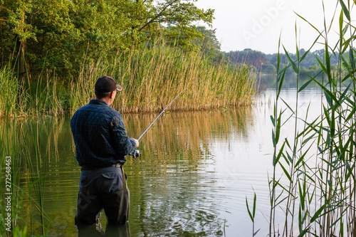 angler standing in the lake and catching the fish