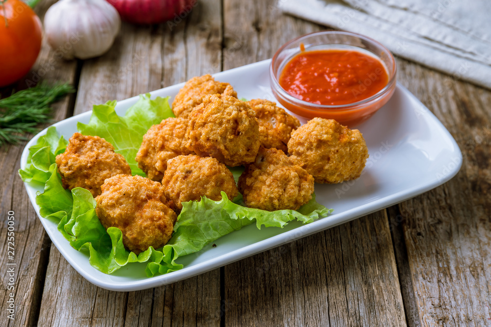 Chicken balls with ketchup on white plate on wooden background Chicken balls with ketchup on white plate on wooden background