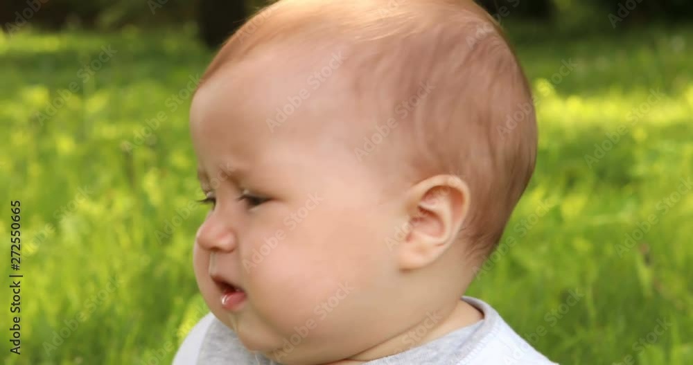 Baby toddler boy ia angry and start crying while sitting in the green grass outdoors. Baby toddler boy ia angry and start crying while sitting in the green grass outdoors.
