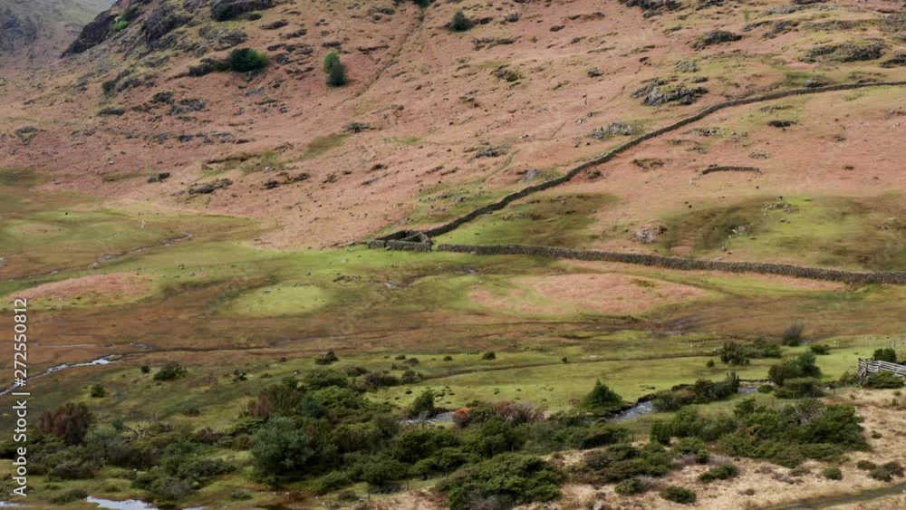 Aerial reveal over a remote river leading up to a rocky hillside and mountains in the distance, Lake District, England Aerial reveal over a remote river leading up to a rocky hillside and mountains in the distance, Lake District, England