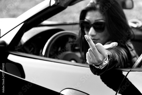 Fotografie young woman shows middle finger out of car