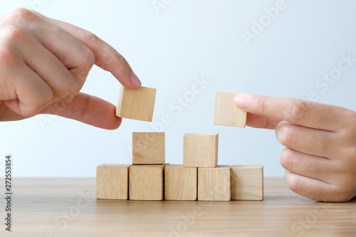 Hand wooden cubes on table over white cement background, mock up, template, banner with copy space for text