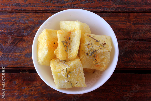 Fotografie boiled and fried cassava (mandioca) in ceramic bowl on rustic wooden table