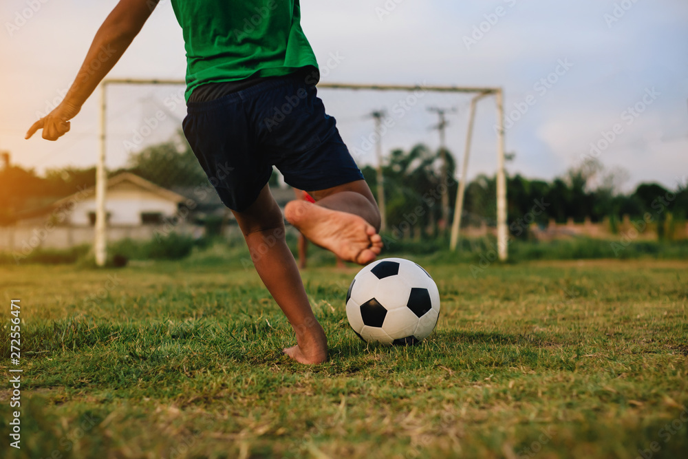 action sport outdoors of a group of kids having fun playing soccer football for exercise in community rural area under the twilight sunset sky.