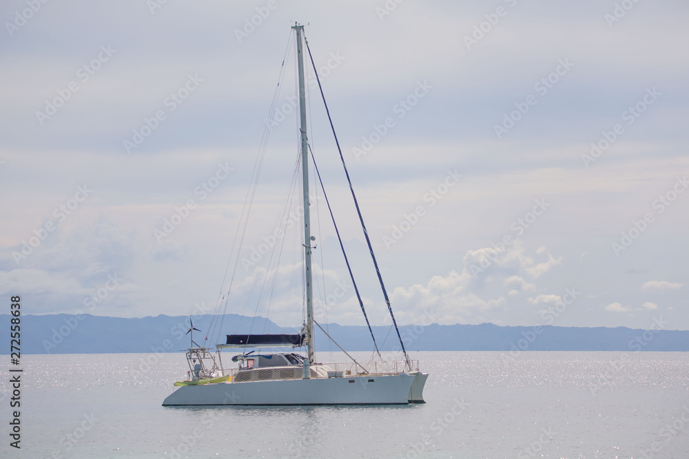 Catamaran sail boat at the coast line anchoring, in a luxury lifestyle summer sunny day photo