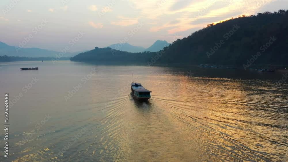 View from above, stunning aerial view of a tourists boat sailing along the Mekong river during a beautiful sunset. Luang Prabang, Laos. View from above, stunning aerial view of a tourists boat sailing along the Mekong river during a beautiful sunset. Luang Prabang, Laos.
