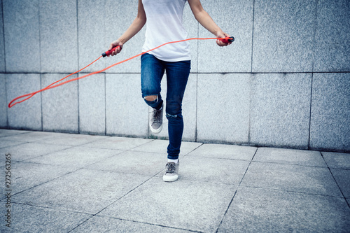 Young fitness woman rope skipping at city