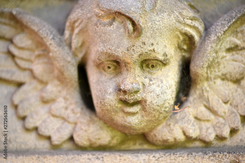 A weathered sandstone sculpture of a little angel.