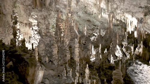 Postojna caves interior pan over stalagmites stalactites. Riding through an illuminated tunnel, part of a cave system in Postojna in Slovenia photo