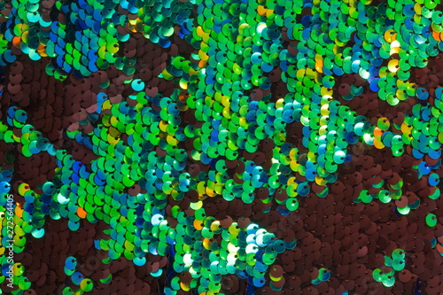 Texture of fabric with round green and black sequins. Shiny abstract fashion texture. Neon trend colors.