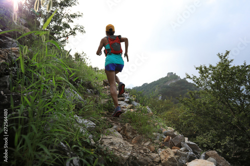 young woman trail runner running at great wall on the top of mountain