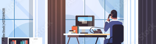 businessman sitting at workplace desk rear view business man using computer while talking on landline phone working process concept creative office interior flat horizontal portrait