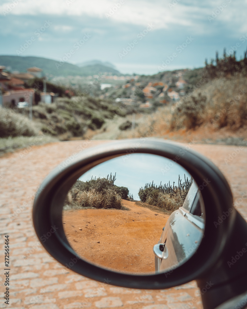 The road behind and ahead the car in the sidemirror of a Mini Cooper
