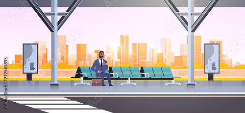 businessman sitting modern bus stop african american business man with suitcase waiting public transport on airport station cityscape background flat horizontal full length