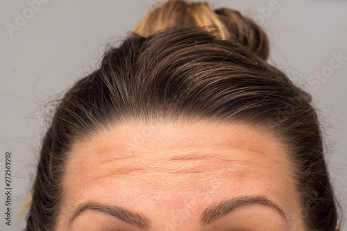 A closeup view on the eyebrows, forehead and hairline of a young Caucasian woman with brunette hair. Health, beauty and cosmetics concept.