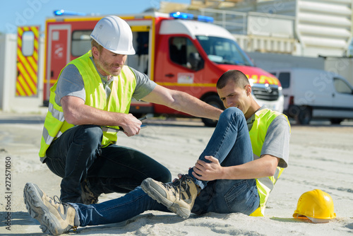 Canvas Print injured lying worker at work being assisted