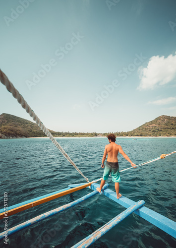 Guy observing the view from a boat in a tropical island