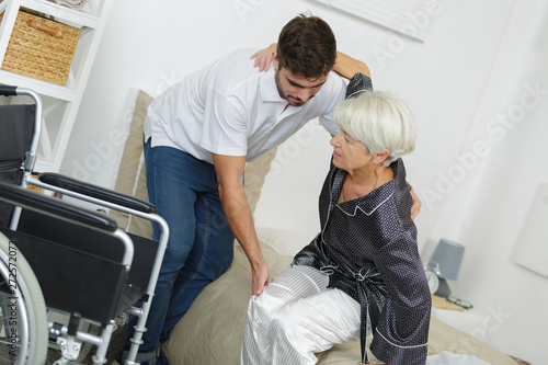 home caregiver helping senior woman getting up