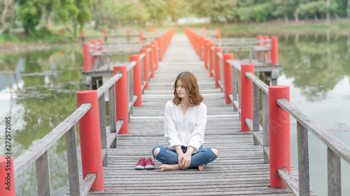 The girl sat on the red bridge and turned right to the side of the shoe.