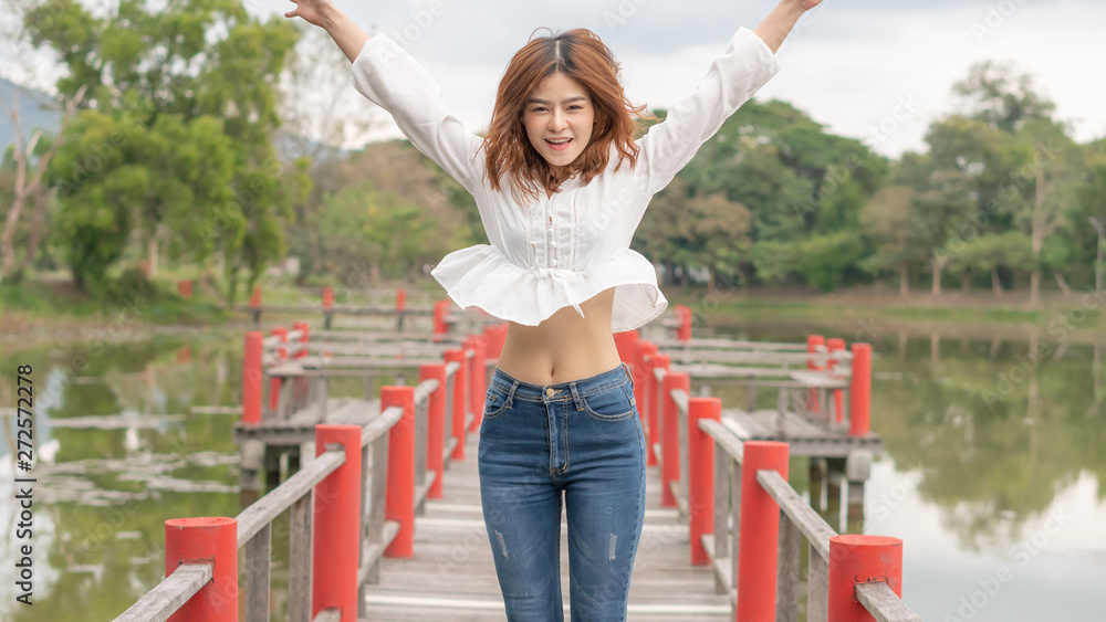 Obraz premium The young woman is jumping on the red bridge with great strength.