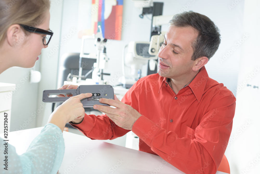 optician showing equipment to patient optician showing equipment to patient