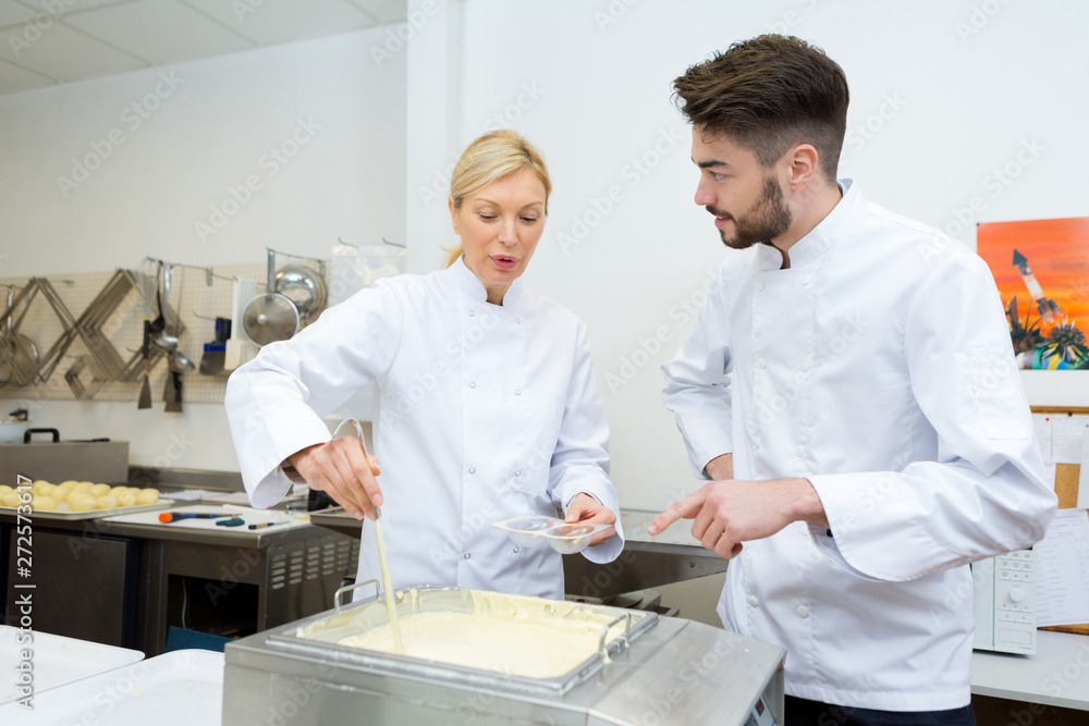 Obraz premium confectioner ladelling melted white choloate into plastic egg-shaped moulds