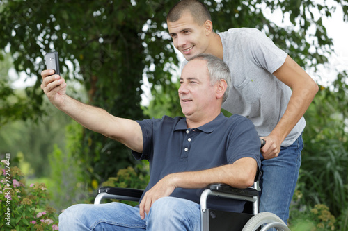 father on wheelchair taking selfie with son