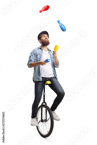 Bearded man on a unicycle juggling with clubs photo
