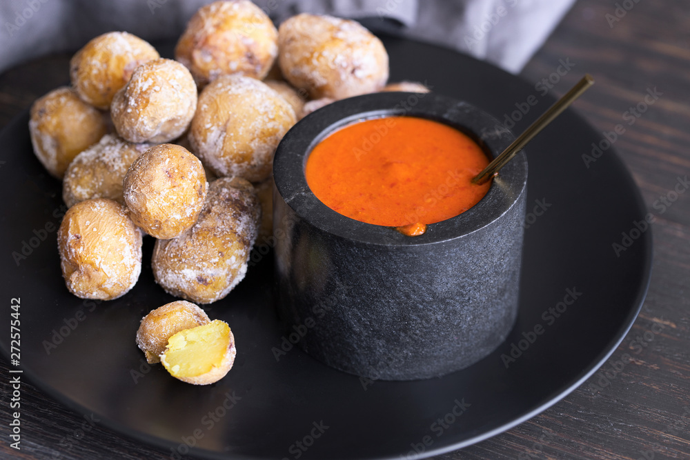 Famous Canary Islands dish, Papas Arrugadas (wrinkly potatoes with salt) and Mojo picon (red sauce) on wood table