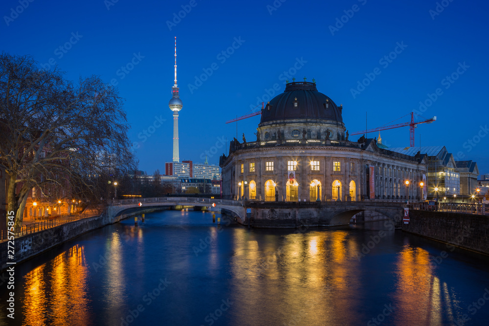 Beautiful view of the illuminated Fernsehturm TV Tower, Bode Museum and its reflections on the Spree River in Berlin, Germany, at dusk.