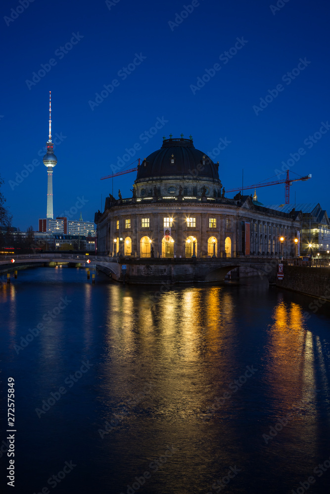Beautiful view of the illuminated Fernsehturm TV Tower, Bode Museum and its reflections on the Spree River in Berlin, Germany, at dusk.