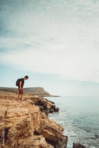 Guy looking at the height of a cliff in Cyprus