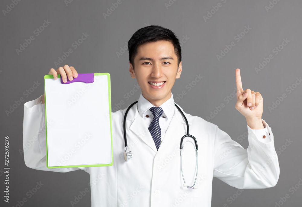 young male doctor holding a clipboard and pointing up young male doctor holding a clipboard and pointing up