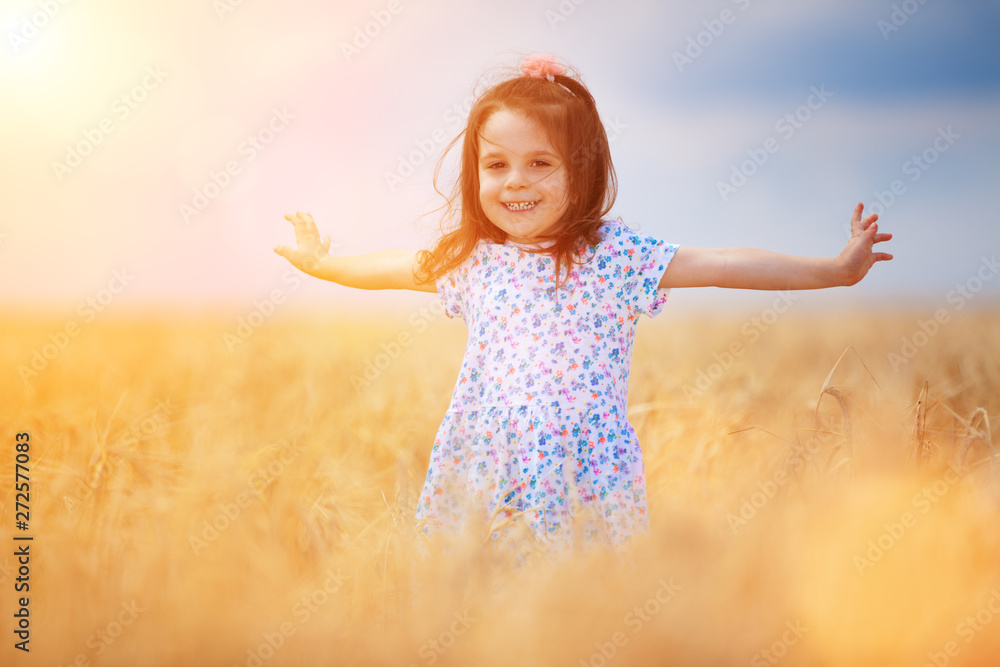 Happy girl walking in golden wheat, enjoying the life in the field. Nature beauty, blue sky and field of wheat. Family outdoor lifestyle. Freedom concept. Cute little girl in summer field Happy girl walking in golden wheat, enjoying the life in the field. Nature beauty, blue sky and field of wheat. Family outdoor lifestyle. Freedom concept. Cute little girl in summer field