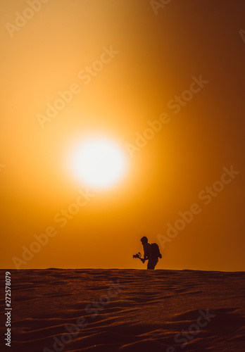 Silhouette of a man walking in the heat of the desert in a hot day © fredchimelli