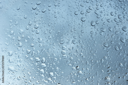 viele kleine Wassertropfen auf einer Scheibe in blau bei Regen