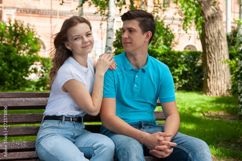 beautiful young couple sitting on a bench in the park