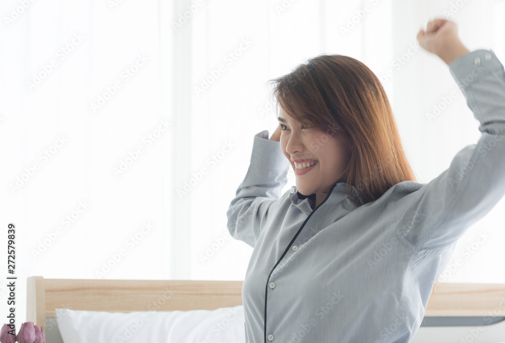 Young beauty Asian woman wake up with happy smile and stretching oneself in bedroom Young beauty Asian woman wake up with happy smile and stretching oneself in bedroom