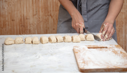 The hostess cuts the dough in the kitchen