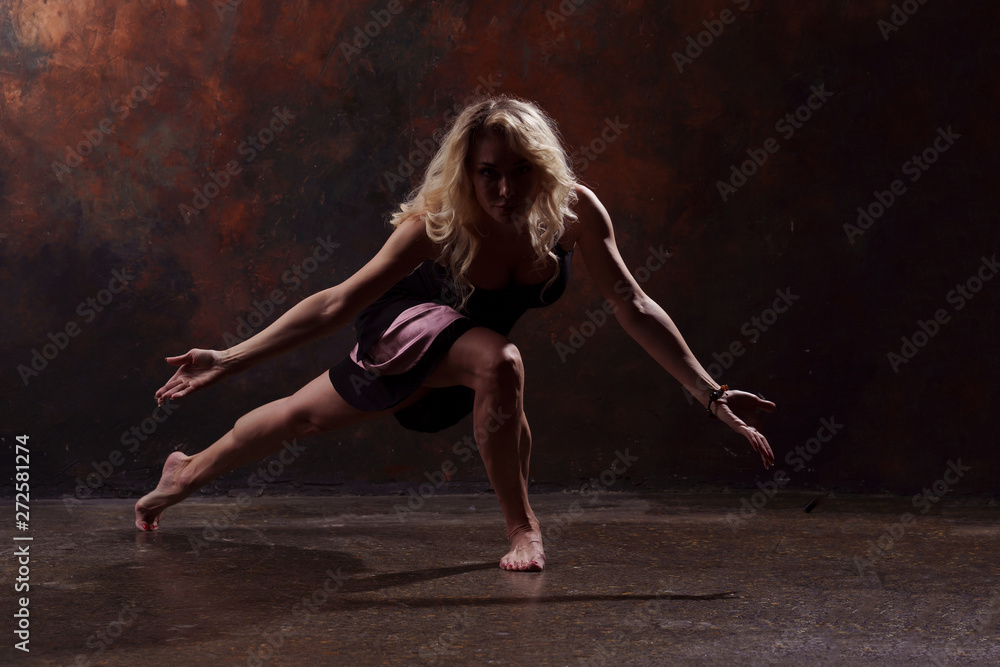 Full-length photo of dancing blonde girl in black dress on brown background Full-length photo of dancing blonde girl in black dress on brown background