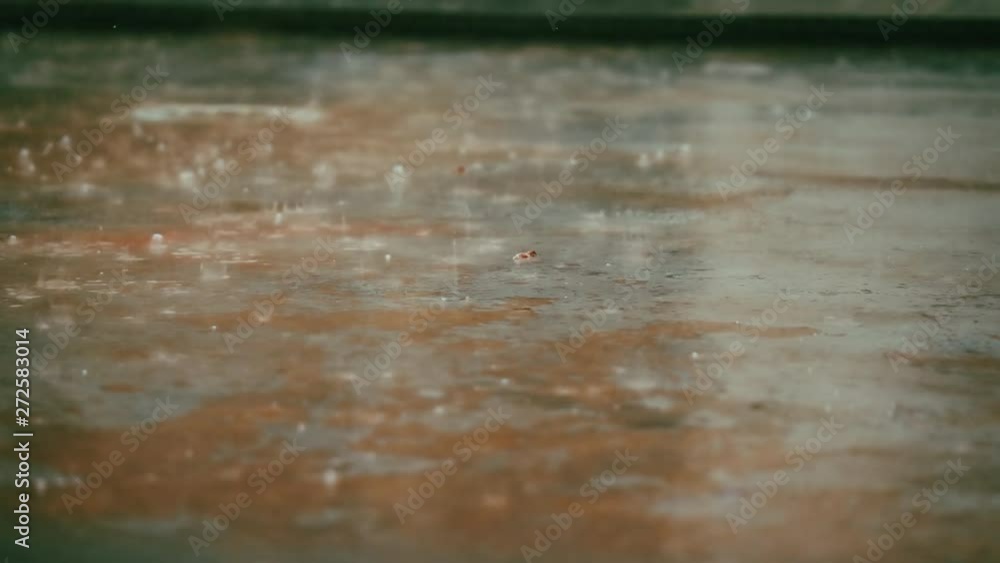 Rain falling down on red pavement, looking from close, close up slow motion Rain falling down on red pavement, looking from close, close up slow motion
