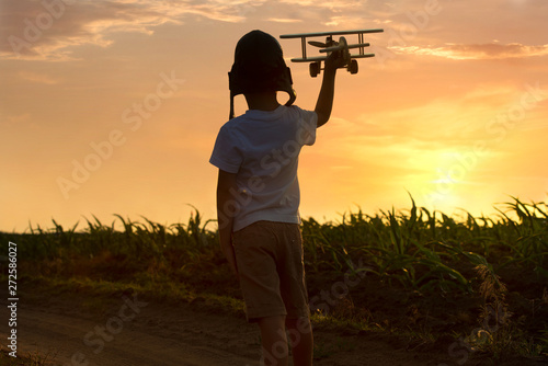 Child pilot aviator with airplane dreams of traveling in summer in nature at sunset 