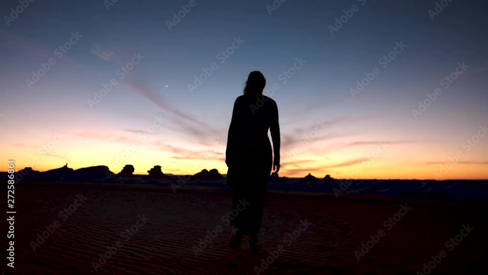 The White Desert & Black Desert in Egypt. Lady walking in the desert at sunset in slow motion with the wind blowing her clothes The White Desert & Black Desert in Egypt. Lady walking in the desert at sunset in slow motion with the wind blowing her clothes