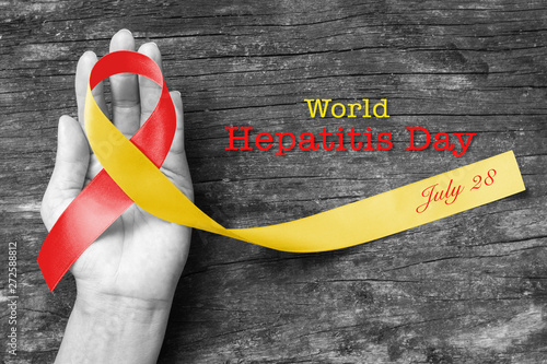 World hepatitis day awareness with red yellow ribbon  (isolated  with clipping path) on person's hand support and old aged wood photo