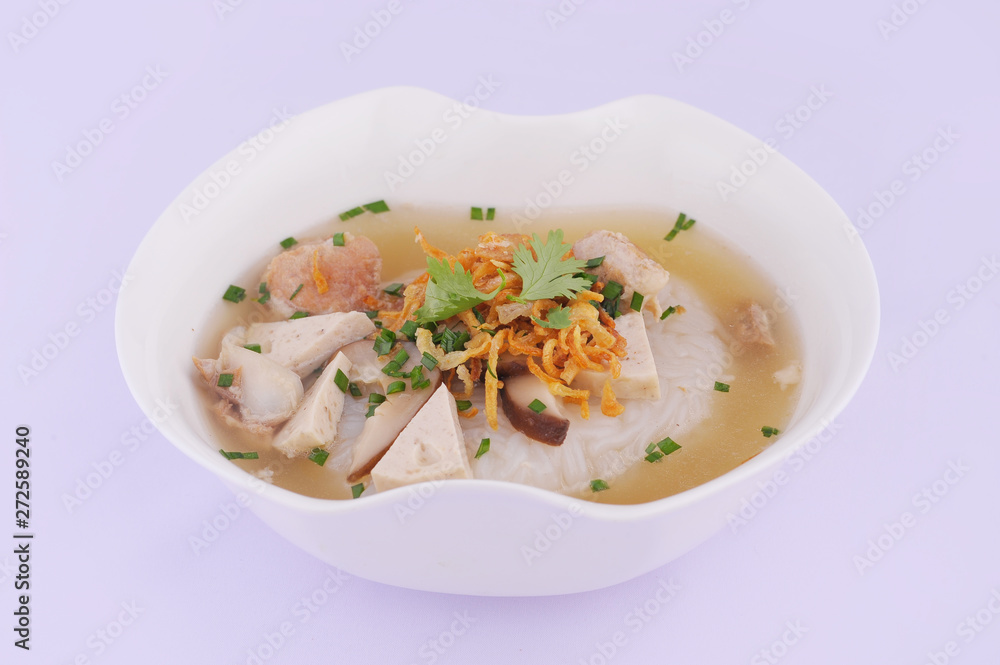 Vietnamese Rice Noodles Soup with pork spare ribs holding in fork and Vietnamese style sausage, deep fried red onion and parsley on wooden table background, popular delicious Vietnamese food